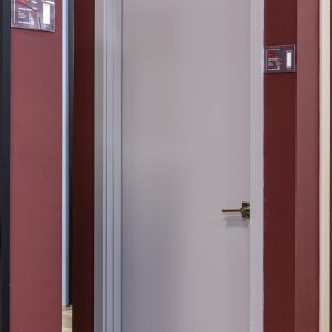 Modern white interior door with chrome handle against burgundy wall in showroom