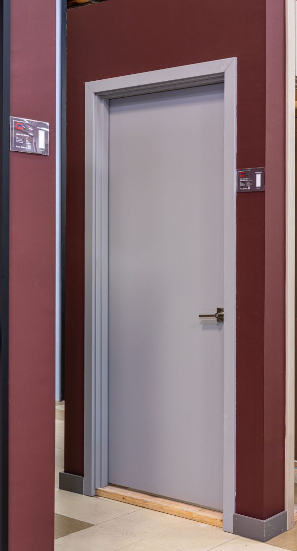 Modern white interior door with chrome handle against burgundy wall in showroom
