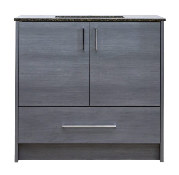 Gray wood-grain bathroom vanity cabinet with dark granite countertop, two cabinet doors with black handles, and one drawer below