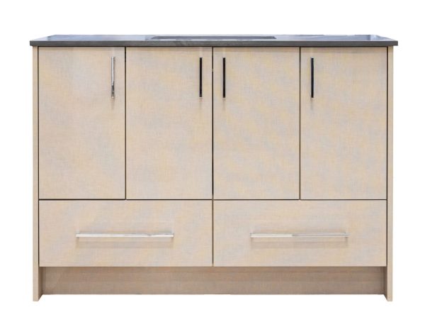 Light natural wood bathroom vanity with four upper cabinet doors and two lower drawers, featuring chrome handles and a dark gray countertop with integrated sink