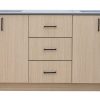 Light wood bathroom vanity with multiple cabinets and drawers featuring black handles