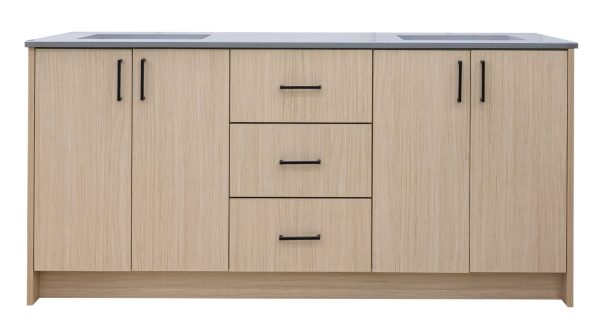 Light wood bathroom vanity with multiple cabinets and drawers featuring black handles
