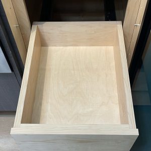 Empty wooden drawer with light wood finish and plywood construction, viewed from above