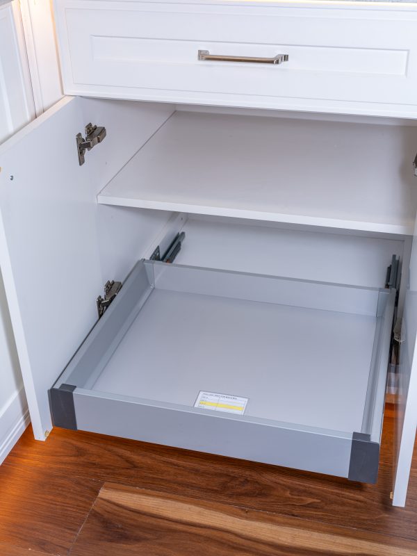 White kitchen cabinet with pull-out drawers open showing empty gray interior storage