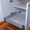 White kitchen cabinet interior showing two shelves and one pull-out drawer with soft-close hardware and metal hinges