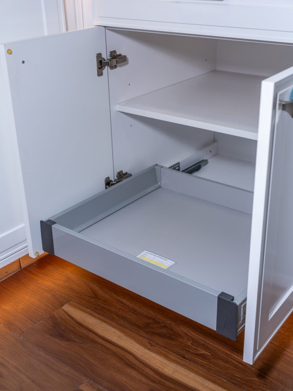 White kitchen cabinet interior showing two shelves and one pull-out drawer with soft-close hardware and metal hinges
