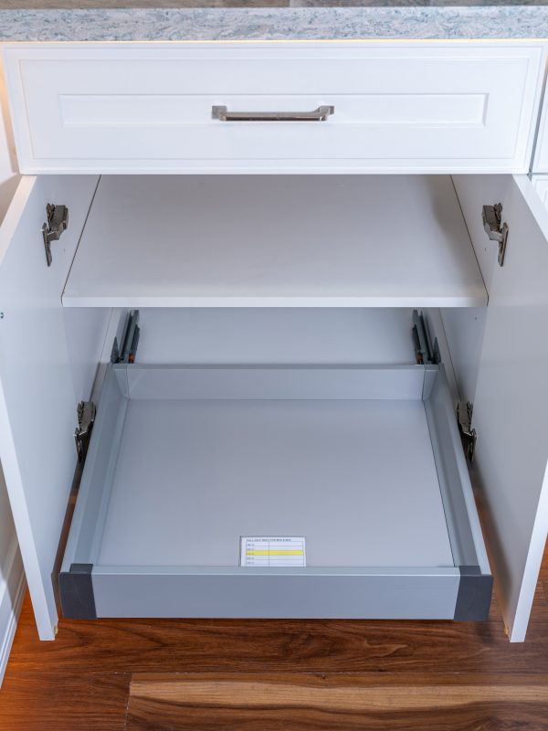Open kitchen cabinet showing two fully extended pull-out drawers with soft-close hardware and internal mounting brackets