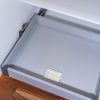 Close-up view of a pull-out drawer mechanism inside a white kitchen cabinet with a yellow installation label visible