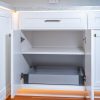 White kitchen cabinet with open doors revealing two pull-out drawers with soft-close hardware and gray interior