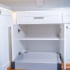 White kitchen cabinet interior with gray pull-out drawer trays and white subway tile backsplash above countertop