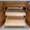Wooden kitchen cabinet with both pull-out drawers fully extended and open, displaying full-depth storage organization