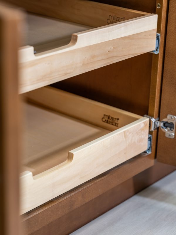 Close-up detail of wooden pull-out drawer slides showing natural wood construction with curved handles and metal bracket hardware in kitchen cabinet