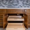 Wooden kitchen cabinet with both pull-out drawers open at different depths, demonstrating dual-drawer storage organization