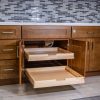 Kitchen cabinet with two pull-out wooden drawers fully extended, showing natural wood construction and metal slide hardware