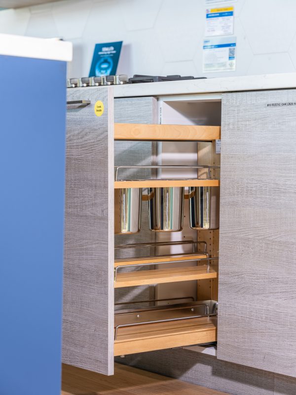 Kitchen cabinet interior showing wooden shelves with metal containers and silver organizational dividers
