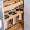 Close-up of wooden pull-out drawer with three circular stainless steel pot holders and multiple shelf levels