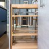 Vertical pull-out cabinet organizer with wooden shelves holding stainless steel storage containers