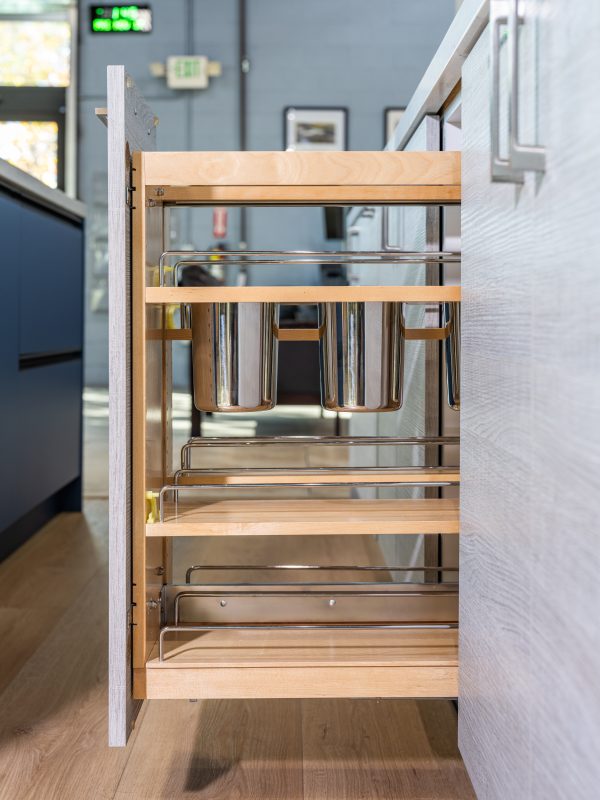 Vertical pull-out cabinet organizer with wooden shelves holding stainless steel storage containers