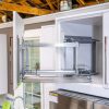 Modern kitchen cabinet with pull-out wire storage shelves and stainless steel appliances