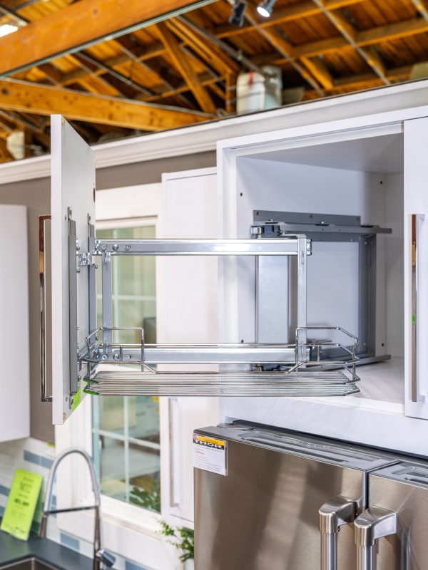Modern kitchen cabinet with pull-out wire storage shelves and stainless steel appliances