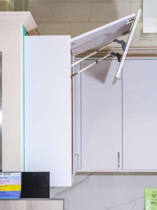 White kitchen cabinet with door open displaying adjustable shelf supports and hinges