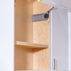 Open kitchen cabinet door revealing wooden shelves with a paper towel holder mounted inside