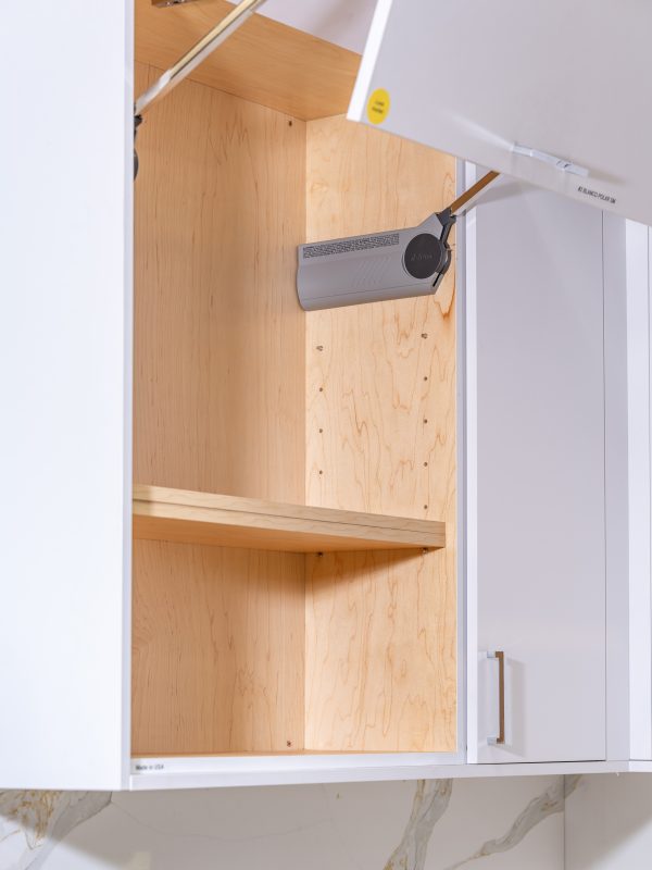 Open kitchen cabinet door revealing wooden shelves with a paper towel holder mounted inside
