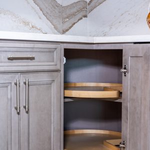 Open corner cabinet with curved wooden lazy Susan shelves and stainless steel hardware, displaying organized storage