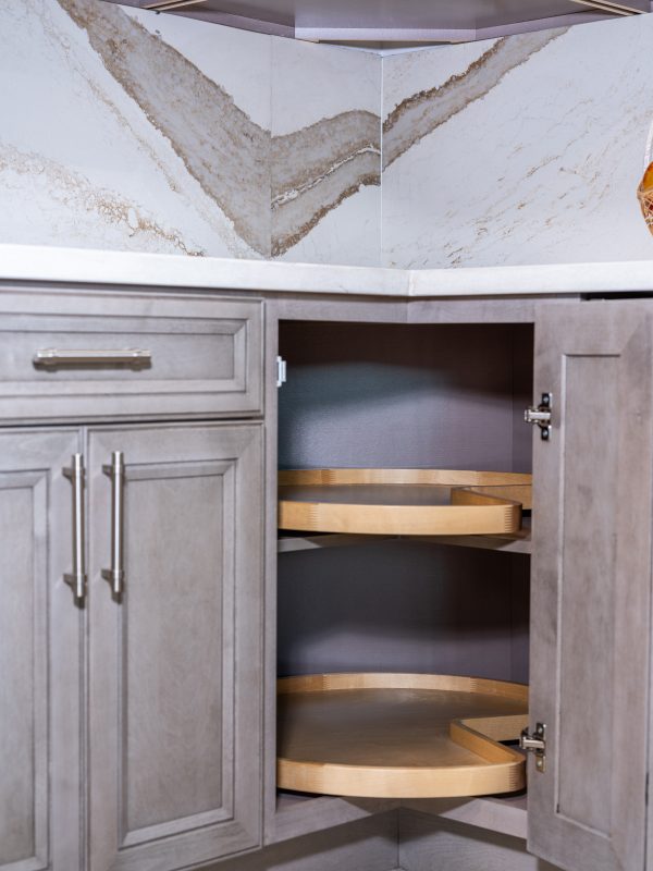 Open corner cabinet with curved wooden lazy Susan shelves and stainless steel hardware, displaying organized storage