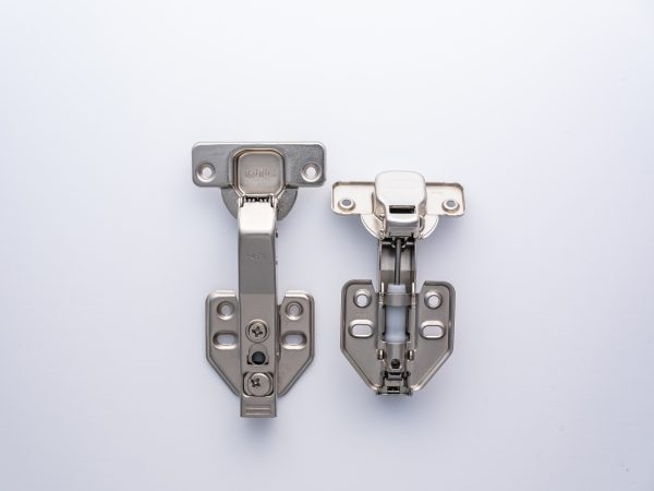 Two metal cabinet hinges with soft-close mechanisms displayed side by side on white background