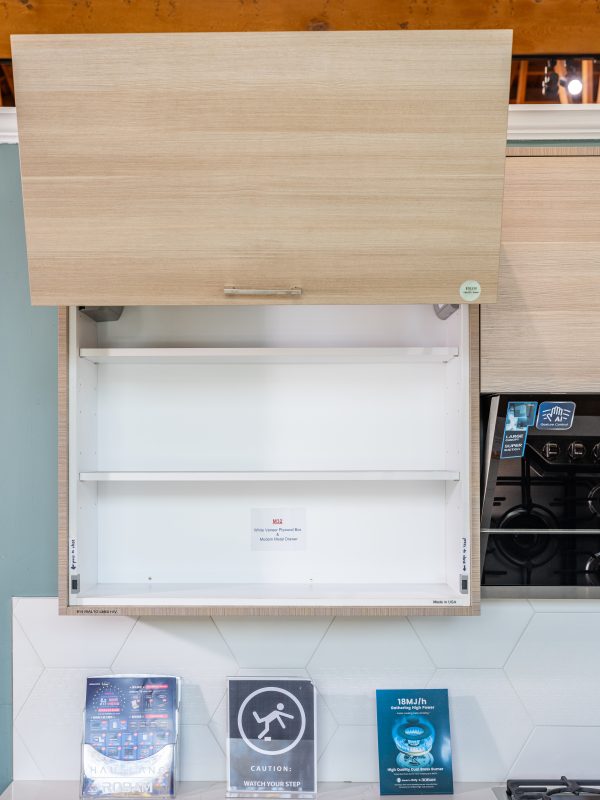 Light wood cabinet with closed upper door and open lower shelves displaying white interior, with caution and product information signs below