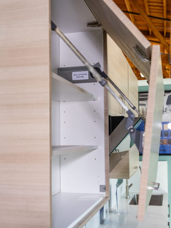Interior view of open wooden cabinet with white shelves and metal support rod, showing 'Exc-Lift System Electric' label inside