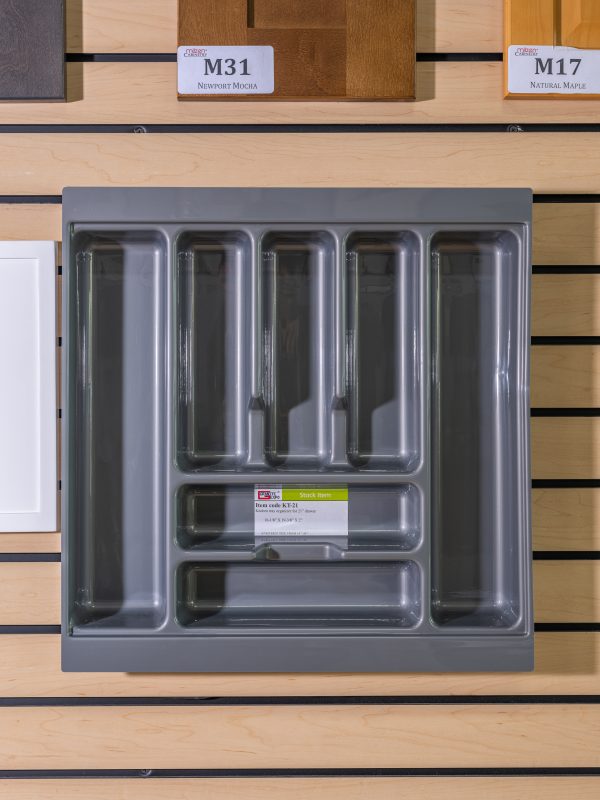 Gray plastic drawer organizer with compartments displayed on wooden shelf next to wood samples labeled M31 and M17