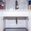 Kitchen sink cabinet with gray pull-out tray beneath marble hexagonal tile backsplash and black faucet
