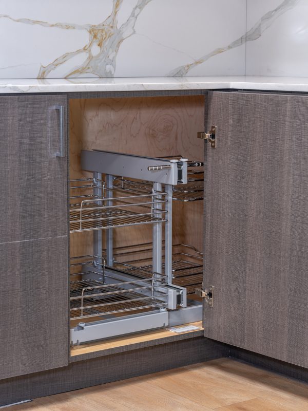 Kitchen corner cabinet with pull-out wire basket organizer system closed showing three-tier chrome shelving design for interior storage