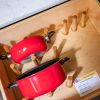 Kitchen drawer organizer with red cookware and wooden peg board storage system