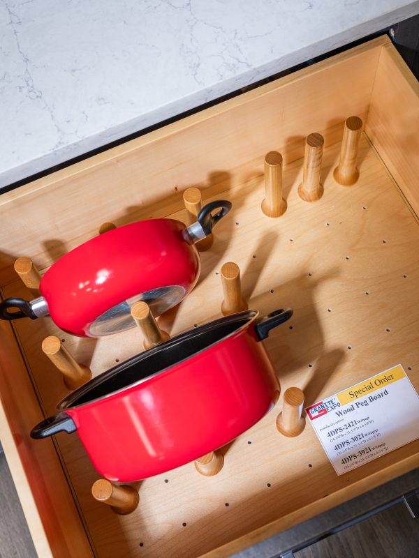Kitchen drawer organizer with red cookware and wooden peg board storage system