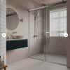 Modern bathroom design with sliding glass shower door, floating black vanity, circular mirror, beige tiled walls, and natural light from window