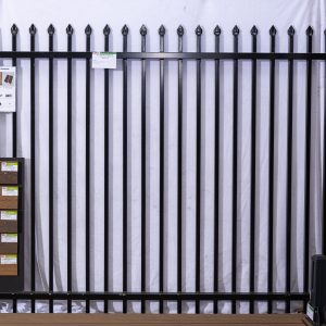 Black ornamental fence display showing multiple pickets with spear-point finials and wood grain finish samples