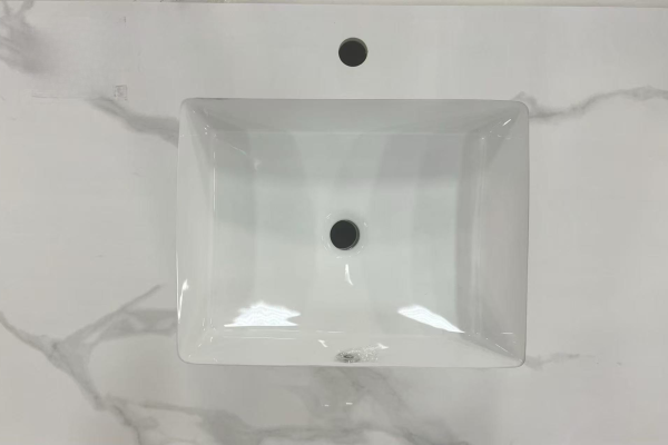 White rectangular ceramic vessel sink with overflow hole and single faucet hole, mounted on marble countertop