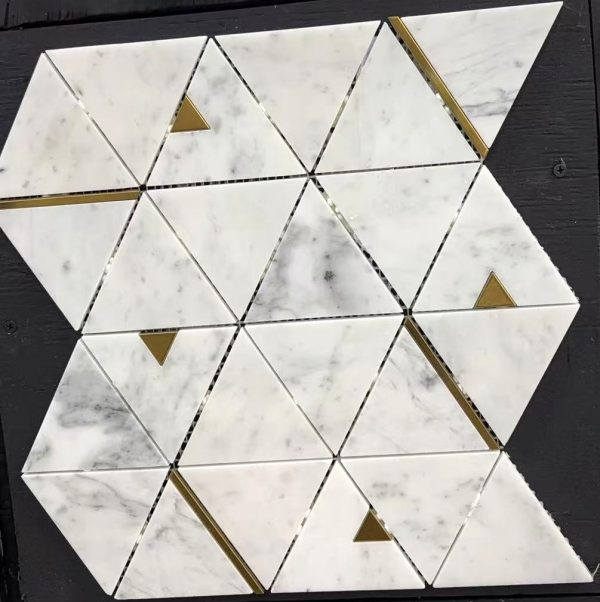 White marble mosaic tile backsplash with geometric triangle pattern and brass metal accents on dark wood surface